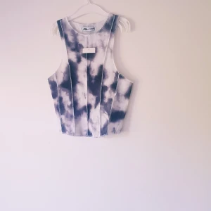 Tie-dye croppad linnetopp FB Sister - Snygg croppad linnetopp från FB Sister i storlek XXS. Toppen har ett svart och vitt tie-dye mönster och är ribbad i materialet. Perfekt för dig som gillar trendiga och unika plagg med sportig vibe.  Ny med lapp så inget att anmärka på 