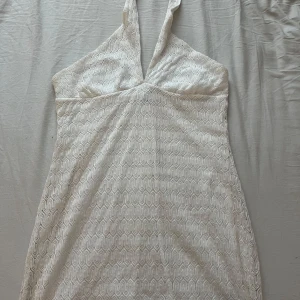 Vit klänning från Divided - Supersöt vit kortklänning från Divided med halterneck och v-ringning. Klänningen har ett vågigt spetsmönster över hela och är fodrad med mjukt tyg. Perfekt för sommarens alla tillfällen och ger en fräsch och trendig look. Passs tyvärr inte mig så den är bara testad!