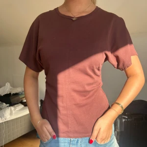 Brun kortärmad t-shirt i bomull - Säljer en basic brun t-shirt med korta ärmar och rund hals. T-shirten har en enkel, clean look och är gjord i mjuk bomull. Passformen är normal och den är perfekt att matcha med jeans för en chill stil.