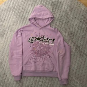 Lila hoodie från Spider - Cool lila hoodie från Spider med ett unikt spindelnätsmönster och prickigt tryck på framsidan. Perfekt för en avslappnad stil med en touch av färg och mönster. Tillverkad i 100% bomull för en bekväm känsla.
