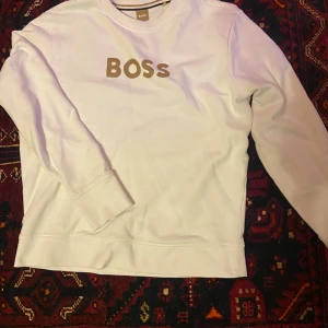 Vit BOSS tröja - Säljer en stilren sweatshirt från Boss. Använd en gång och är i perfekt skick. Nypriss ligger på 1499kr säljer för 599kr. Tröjan sitter som S för dig som är mellan 170-175cm. Kom privat för fler frågor!
