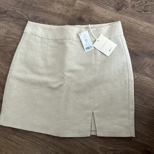 Beige kjol med slits - Snygg beige kjol med en liten slits framtill. Perfekt för en stilren look. Kjolen har en dragkedja bak för enkel på- och avtagning. Skickas mot frakt eller kan mötas upp i Norrköping💕🌸