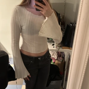 Vit ribbad tröja med vida ärmar - Säljer en stilren vit ribbad tröja med vida ärmar. Tröjan har en tight passform och är perfekt för en trendig look. Passar bra till både jeans och kjol.