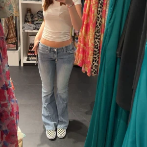 Ljusblå true religion jeans - Snygga ljusblå bootcut jeans med låg midja och klassisk femficksdesign. Perfekta för en avslappnad stil. Kombinera med sneakers för en cool look.                                                                                  Storlek 27