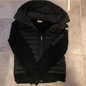 Moncler cardigan - Säljer en snygg svart jacka från Moncler som passar perfekt i väder som detta, har dock en liten defekt då moncler labeln sitter har lossnat på en sidan men är en enkel fix😃
