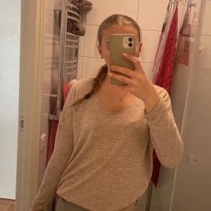 Beige tröja från Hailys - Säljer en beige tröja från Hailys med v-ringning. Tröjan har långa ärmar och en mjuk, bekväm passform. Perfekt för en avslappnad stil.