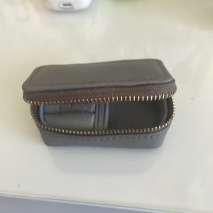 Grå plånbok med dragkedja - Säljer en kompakt och stilren grå plånbok med dragkedja. Perfekt för att förvara småsaker eller smycken. Den har en praktisk design med ett fack inuti och en säker dragkedja runtom.