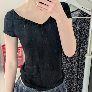 Svart v-ringad topp - Säljer en stilren svart v-ringad lite flowig topp med korta ärmar. Perfekt för en enkel och klassisk look. Har tagit bort lappen. Är XS men skulle passa S