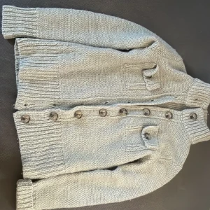 Grå stickad kofta från Boomerang - Säljer en stilren grå stickad kofta från Boomerang. Koftan har långa ärmar och knappar framtill samt ribbade muddar och krage. Perfekt för kyliga dagar! 🧥