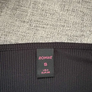 Svart ribbad topp från ROMWE - Säljer en svart ribbad topp från ROMWE i storlek S. Toppen har lång ärm, v-ringning och snygg rynkdetalj framtill. Perfekt att styla med jeans eller kjol för en trendig look.