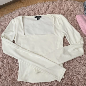 Vit långärmad topp med fyrkantig ringning från Gina Tricot - Säljer en stilren vit långärmad topp från new yorker med snygg fyrkantig ringning. Perfekt att matcha med både jeans och kjol. Tunn och mjuk i materialet, sitter snyggt och är enkel att styla.