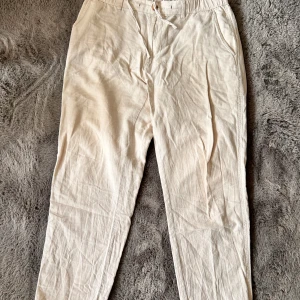  linnebyxor - Säljer ett par vita linnebyxor med normal passform och raka ben. Perfekta för varma dagar och en avslappnad stil.