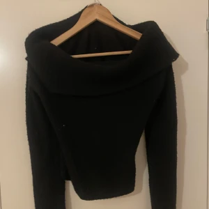 Svart stickad offshouldertröja från H&M - Säljer en svart stickad tröja från H&M med bred offshoulderkrage. Tröjan har lång ärm och är mjuk och varm, perfekt för kyligare dagar. Snygg och enkel att matcha med olika outfits.