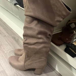 Beige mockastövlar med klack  - Säljer ett par snygga beige stövlar i mocka från Anna Field. De har hög klack, rund tå och dragkedja på insidan. Använda 1-2 gånger så iprincip nyskick!