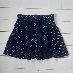 Prickig kjol Superdry - Jättefin prickig kjol från märket Superdry🌸Kjolen har blivit sparsamt använd och har därmed inga tydliga defekter. Kjolen är mörkblå med vita prickar. Den har knappar framtill och på dem står det Superdry. Kjolen har även fickor på sidorna, vilket kan vara mycket praktiskt. Den har resor baktill i midjan, framsidan har ej resor. Nypris 499kr. Skriv gärna vid frågor eller funderingar☺️