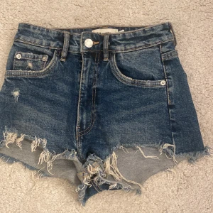 Blå jeansshorts med fransar från Zara - Snygga blå jeansshorts från Zara med hög midja och slitningar.  