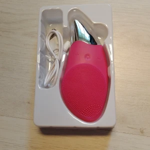Vibrerande mjuk ansiktsrengöring borste anti-aging porrengörare - Elektrisk ansiktsrengöringsborste i rosa silikon med silverfärgad topp. Borsten har små silikonpiggar för djuprengöring och medföljande USB-laddningssladd. Perfekt för att rengöra huden och ta bort sminkrester.