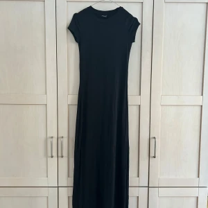 Svart långklänning från Gina Tricot - Säljer en svart långklänning från Gina Tricot. Klänningen har korta ärmar och rund halsringning. Enkel och stilren modell som passar perfekt till många tillfällen. Materialet känns mjukt och följsamt.