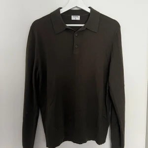 Olivgrön pikétröja från Filippa K - Säljer en stilren olivgrön pikétröja från Filippa K. Tröjan har klassisk krage, knäppning med tre knappar och långa ärmar. Tillverkad i ett mjukt material som känns skönt mot huden. Perfekt för en clean och avslappnad look.