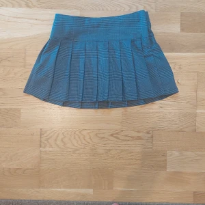 Rutig plisserad kjol från H&M - Snygg rutig plisserad kjol från H&M i blå och svarta toner. Kjolen har bred linning och klassiskt rutmönster, perfekt för en trendig look. Sidodragkedja för enkel på- och avtagning.💗💗