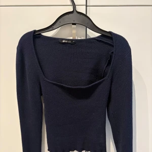 Mörkblå ribbad topp från Gina Tricot - Säljer en mörkblå ribbad topp från Gina Tricot med lång ärm och fyrkantig ringning. Kortare vid magen, och slits nere vid handen🥰
