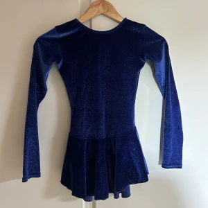 Blå sammetsklänning från Mondor - Säljer en glittrig blå sammetsklänning från Mondor. Klänningen har en klassisk rund halsringning och ett utställt kjolparti. Storlek 12-14 år (ca 150cm). Väldigt sparsamt använd. Nypris ca 1070kr. Perfekt för ditt barn som gillar dans eller konståkning!