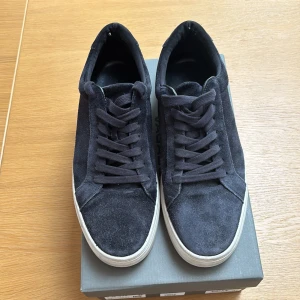 Svarta sneakers från Vagabond i mocka - Säljer ett par användna svarta sneakers från Vagabond i mjuk mocka med vita platta sulor och klassisk snörning🤩. Skorna har en stilren och enkel design som passar till det mesta. Perfekta för dig som gillar en clean look💰. Säljer skorna eftersom dem blivit för små för mig. 