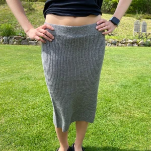 Grå ribbad stickad kjol - Nyskick!Säljer en grå ribbad stickad kjol med midihög midja och rak passform. Kjolen är mjuk och stretchig, perfekt för en chill och stilren look. Passar lika bra till sneakers som boots. Enkel att matcha med olika toppar. Innehåller 30% ull, så passar utmärkt till hösten också. Mycket användbar kjol.