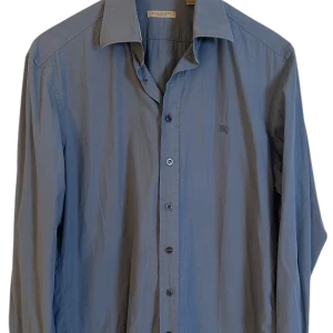 Burberry skjorta  - Burberry skjorta med monogram. Storlek L. Skick 9/10 super fin även nystrykt. Färg Ljusblå. Pris 890kr finns att köpa på våran hemsida Fashionels.com