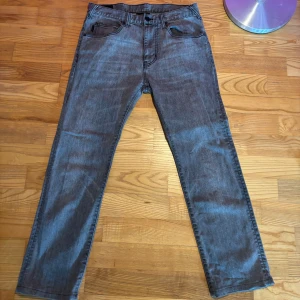 Gråa Armani jeans - Säljer ett par grå Emporio Armani jeans med klassisk femficksdesign och raka ben. Byxorna har knapp och dragkedja i gylfen. Midjemått W30 och längd L32. Perfekta för en stilren och avslappnad look.