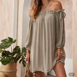 Beige offshoulder summer klänning - Säljer en beige offshoulder klänning med långa ärmar och avslappnad passform. Klänningen har justerbara resårer upptill och är tillverkad i ett lätt, vävt material som ger en luftig känsla. Perfekt för varma dagar och enkel att styla med smycken.