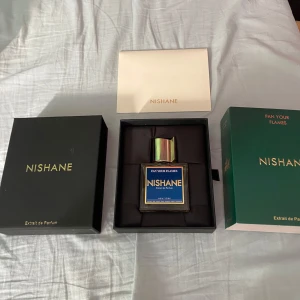 Nishane Fan Your Flames Extrait de Parfum - Exklusiv parfym från Nishane, Fan Your Flames, i en elegant fyrkantig glasflaska med blå etikett och stor silverfärgad kork. Doften är intensiv och unik, perfekt för dig som vill sticka ut med en lyxig signaturparfym. 45/50 ml