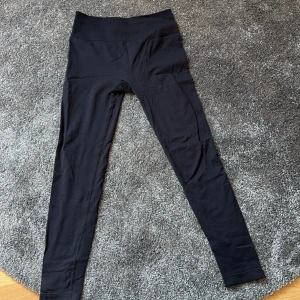 Svarta leggings från Relode - Svarta leggings från Relode med hög midja och tight passform. Perfekta för träning eller en aktiv vardag. Tillverkade i ett stretchigt syntetmaterial som ger bra rörelsefrihet.