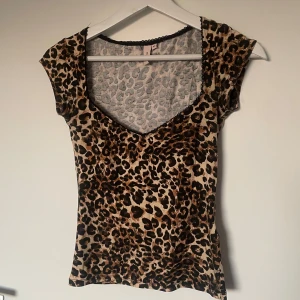 Leopardmönstrad topp från Nelly - Snygg och populär/trendig leopardmönstrad topp från Nelly. Toppen har en dekorativ spetskant vid halsringningen och är i storlek xs. Mycket bra skick, endast använd en gång!  