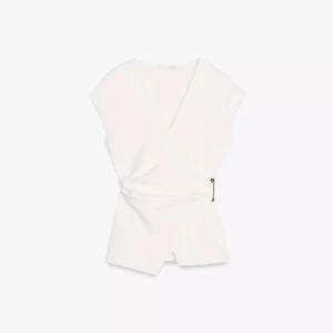 Vit omlottopp med gulddetalj - Snygg vit omlottopp med v-ringning och ärmlös design. Toppen har en unik guldfärgad metallpinne som detalj i sidan och en stilren, något croppad passform. Perfekt för dig som gillar minimalistisk och modern stil.