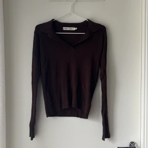 Brun ribbad tröja från InWear - Mörkbrun ribbstickad tröja från InWear med krage och v-ringning. Långärmad modell i mjukt material som sitter snyggt och har en klassisk men trendig look. Perfekt att styla med jeans eller kjol för en clean vibe.