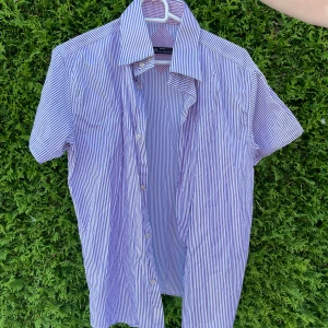 Randig kortärmad skjorta från Zara - Fräsch kortärmad skjorta från Zara med smala blå och vita ränder. Klassisk krage och knappar framtill.