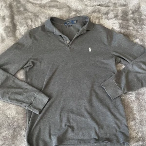 Ralph Lauren tröja  - Säljer en klassisk grå långärmad pikétröja från Polo Ralph Lauren. Tröjan är i storlek S och sitter bra på och är i riktigt bra skick. Tveka inte på att höra av er vid frågor och funderingar. Priset går att diskuteras