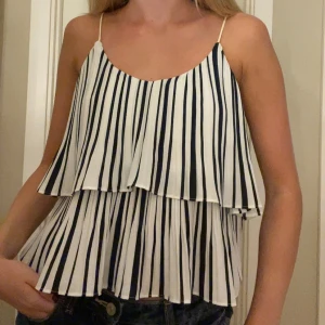 Randig plisserad linnetopp - Superfin vit och marinblå randig linnetopp med tunna axelband och plisserade volanger. 