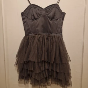 Silver grå rock Princess klänning  - Klänning med smala axelband och markerad bustier. Kjolen har flera lager volang i tunn tyll som ger extra fluff. Perfekt för dig som vill ha en edgy och snygg look med mycket attityd.
