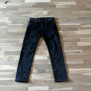 Levi's 502 svarta jeans straight fit - Säljer ett par Levi's Premium 502 jeans i svart tvättad denim. Modellen har rak passform med klassiska fem fickor, knapp och dragkedja i midjan. Snyggt läderpatch bak och diskret Levi's-röd etikett på fickan. Perfekt för dig som gillar en clean och tidlös look.