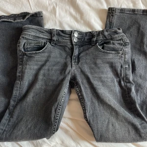 Mörkgrå bootcut jeans med dubbla knappar - Snygga mörkgrå jeans med bootcut passform och dubbla silverfärgade knappar i midjan. Klassisk femficksmodell med lock på bakfickan. Från Gina tricot men lappen är borta. Pris kan diskuteras men sänker helst inte så mycket. 