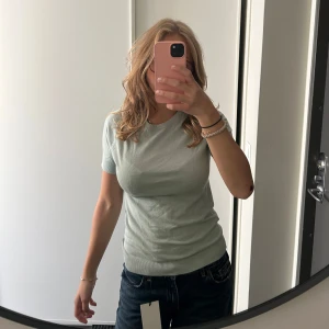 Ljusgrön topp - Säljer en ljusgrön finstickad topp från Mango i storlek M men passar även S. Modellen är enkel med rund hals och korta ärmar, och har en slim passform som sitter snyggt mot kroppen. I nytt skick💕