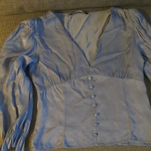 Ljusblå blus med knappar från Zara - PRIS KAN DISKUTERAS!! Supersöt ljusblå blus från Zara med v-ringning. Jag har klippt av lite längst ner på ärmarna då jag inte gillade hur den satt. Så de kvar vara lite ojämna men det är bara att klippa till hur man vill ha det men annars ser det bra ut när den är så, har använt den många gånger efter jah klippte den 💕🥰