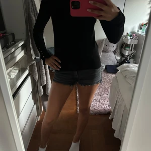 Svarta jeansshorts - Säljer ett par svarta jeansshorts med låg midja och rå, fransig kant. Klassisk femficksmodell med knapp och dragkedja framtill. Perfekta för varma dagar och har en cool, avslappnad vibe. Från barnavdelningen på gina t