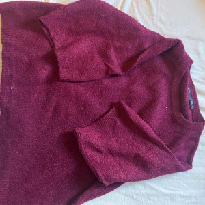 Vinröd stickad tröja från 157 - Vinröd stickad tröja från 157 med korta ärmar och rund halsringning. Tröjan har en enkel och stilren design, perfekt för lager-på-lager och passar till många olika outfits. Mjuk och skön känsla tack vare det stickade materialet.