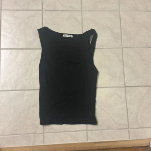 Svart ärmlös linnetopp från Zara - En svart, enkel och stilren linnetopp från Zara. Toppen är ärmlös med rundad halsringning och rak passform, perfekt att matcha med jeans eller kjol. Mjuk och stretchig bomullskänsla som gör den superbekväm att bära.