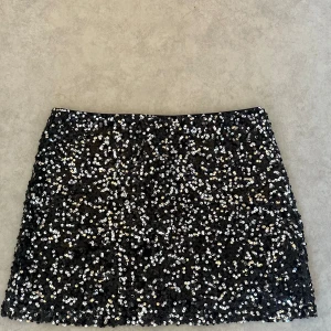 Svart paljettkjol från ASOS Design - Glittrig svart kortkjol från ASOS Design, täckt med silvriga paljetter som ger en riktigt festlig vibe. Kjolen har en rak passform och dragkedja bak för enkel på- och avtagning. Perfekt för dig som vill sticka ut med lite extra bling. Passar perfekt för festival eller fest 🌸