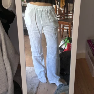 Vita linnebyxor med resårmidja - Säljer ett par vita linnebyxor med avslappnad passform och resår i midjan. Byxorna har raka ben och sidfickor, perfekta för en chill och luftig stil. Materialet är tunt och svalt, vilket gör dem grymma för varmare dagar.