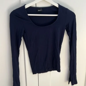 Mörkblå långärmad topp Gina Tricot - En basic mörkblå långärmad topp från Gina Tricot med rund halsringning. Toppens passform är slim och den är tillverkad i mjuk bomull, perfekt att styla med jeans eller kjol för en clean look.